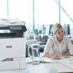 Two women working in an office next to a Xerox® VersaLink® C625 Colour Multifunction Printer