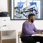 Men working on a laptop in front of a Xerox® VersaLink® C415 Colour Multifunction Printer