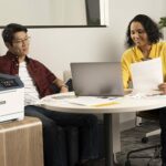 Two people in the office next to the Xerox® C410 Colour Printer