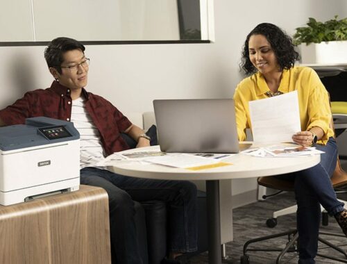 Two people in the office next to the Xerox® C410 Colour Printer